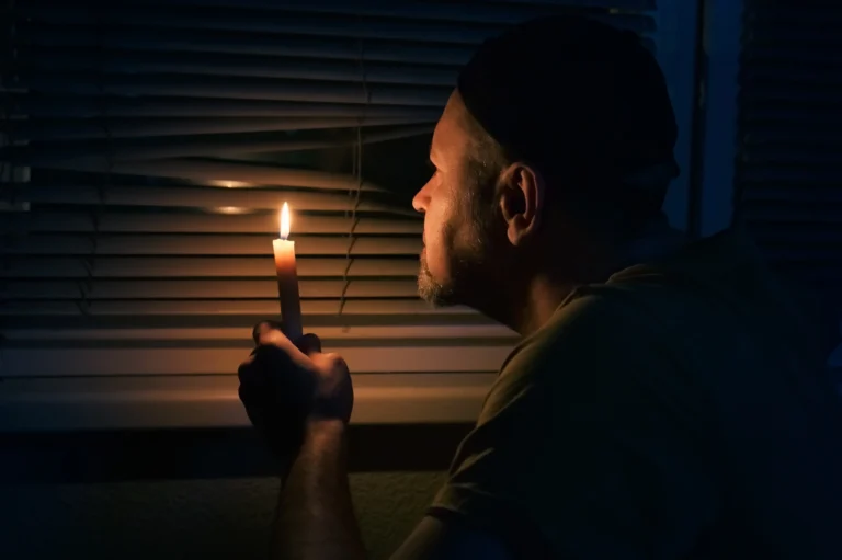 man with candle in dark room